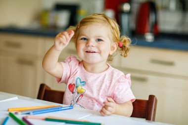Kalemle resim yapmayı öğrenen sevimli bir bebek. Küçük çocuk renkli keçeli kalemlerle evde resim çiziyor. Evde ya da çocuk odasında renkler deneyen sağlıklı, mutlu bir kız.