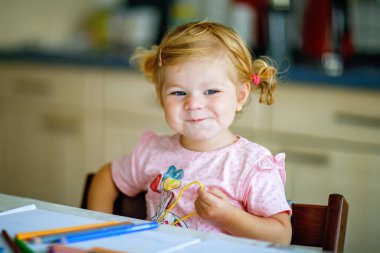 Kalemle resim yapmayı öğrenen sevimli bir bebek. Küçük çocuk renkli keçeli kalemlerle evde resim çiziyor. Evde ya da çocuk odasında renkler deneyen sağlıklı, mutlu bir kız.