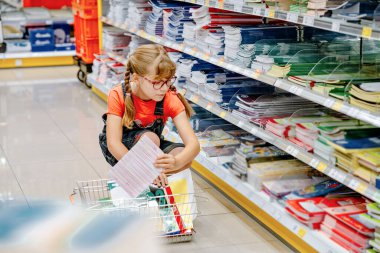 Gözlüklü, not defteri, kalem ve okul gereçleri satan sevimli ilkokul kızı. Okul konseptine geri dönelim. Çocuk yeni okul yılına hazırlanıyor. Gerçek hayat, gerçek insanlar..