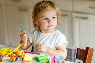 Evinde renkli kille sevimli, küçük bir kız. Sağlıklı bir bebek çocuk yuvasında ya da oyun okulunda hamur oynarken oyuncak yaratıyor. Kil kalıbı çıkaran küçük bir çocuk, yaratıcı aktivite.