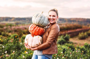 Çiftlikte ya da tarlada üç farklı balkabağı olan mutlu genç çiftçi kadın. Şükran Günü ya da Cadılar Bayramı hazırlığı.