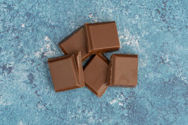 Milk chocolate pieces isolated on background from top view