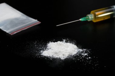 Kokain ya da diğer yasadışı uyuşturucular, beyaz toz, şırınga, siyah parlak arka planda izole