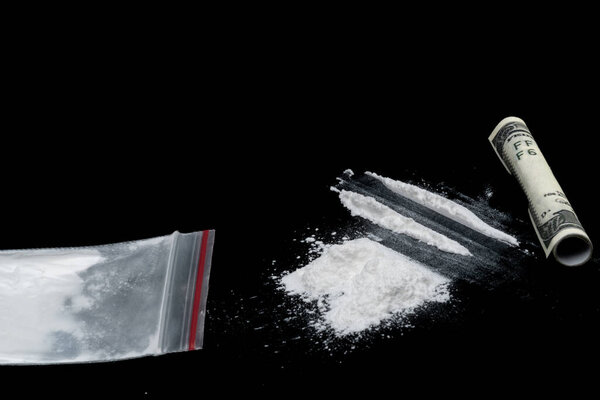 Cocaine or other illegal drugs, white powder, syringe, isolated on black glossy background