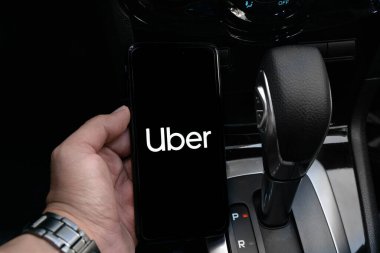 Uber sürücüsü akıllı telefonu arabada tutuyor. Uber, internet üzerinden ulaşım hizmeti sunan bir Amerikan şirketidir. Kullanıcı Uygulaması