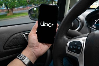 Uber sürücüsü akıllı telefonu arabada tutuyor. Uber, internet üzerinden ulaşım hizmeti sunan bir Amerikan şirketidir. Kullanıcı Uygulaması