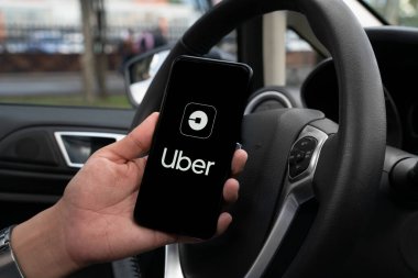Uber sürücüsü akıllı telefonu arabada tutuyor. Uber, internet üzerinden ulaşım hizmeti sunan bir Amerikan şirketidir. Kullanıcı Uygulaması