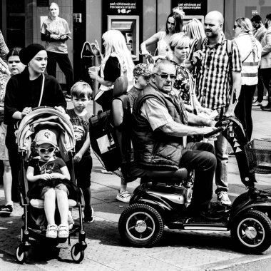 Epsom Surrey, Londra İngiltere, Haziran 03: 22, Elektrikli Mobilite Scooter 'da oturan yaşlı bir adam Bir itme sandalyesinde küçük bir çocuğun yanında ya da kalabalık bir çadırda bebek arabasıyla geziyor.