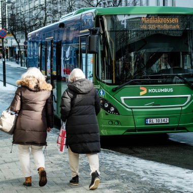 Stavanger, Norway, March 10 2023, Two Middle Aged Women Walking Past A Green Kolumbus Single Deck Bus clipart
