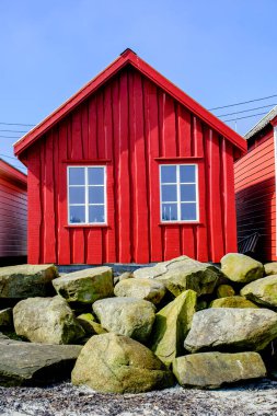 Olberg; Olbergstranden; Raege; Norveç; 20 Mayıs 2023, Row or Line of Rourful Beach Huts with Rocks and Boulders Sea Defences