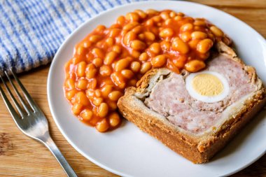 Londra İngiltere, Haziran 06 2025, Bir dilim domuz eti ve fırınlanmış fasulyeli yumurta klasik galası turtası.