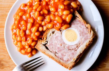 Londra İngiltere, Haziran 06 2025, Bir dilim domuz eti ve fırınlanmış fasulyeli yumurta klasik galası turtası.