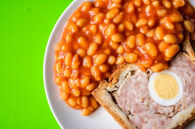 Londra İngiltere, Haziran 06 2025, Bir dilim domuz eti ve fırınlanmış fasulyeli yumurta klasik galası turtası.