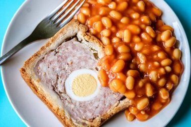 Londra İngiltere, Haziran 06 2025, Bir dilim domuz eti ve fırınlanmış fasulyeli yumurta klasik galası turtası.