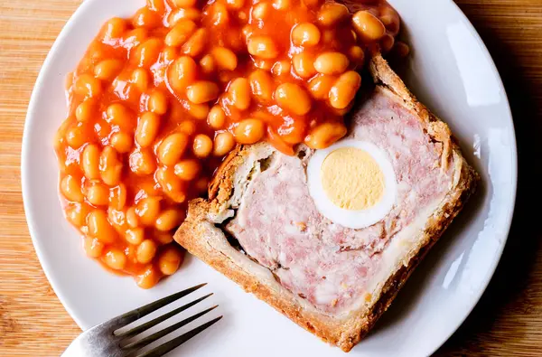 Londra İngiltere, Haziran 06 2025, Bir dilim domuz eti ve fırınlanmış fasulyeli yumurta klasik galası turtası.