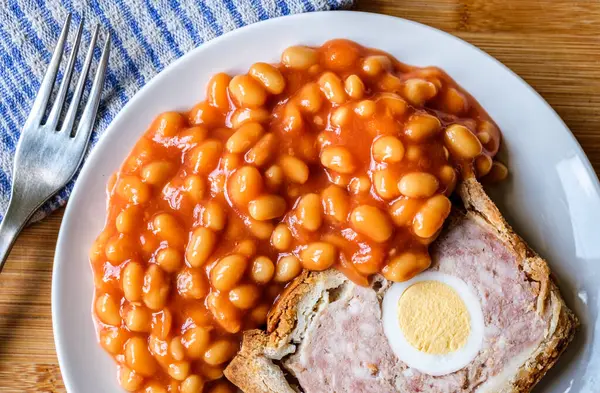 Londra İngiltere, Haziran 06 2025, Bir dilim domuz eti ve fırınlanmış fasulyeli yumurta klasik galası turtası.