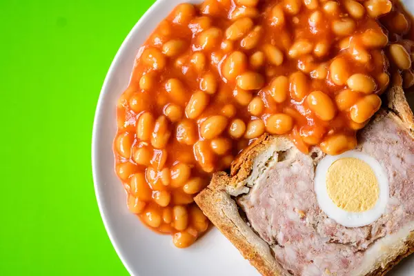 Londra İngiltere, Haziran 06 2025, Bir dilim domuz eti ve fırınlanmış fasulyeli yumurta klasik galası turtası.