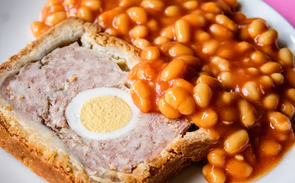 Londra İngiltere, Haziran 06 2025, Bir dilim domuz eti ve fırınlanmış fasulyeli yumurta klasik galası turtası.