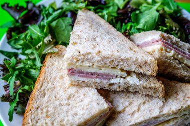 Londra İngiltere, 14 Temmuz 2025, Ev yapımı jambonlu ve peynirli sandviç dilimlenmiş kahverengi ekmek ve yeşil salata yaprakları