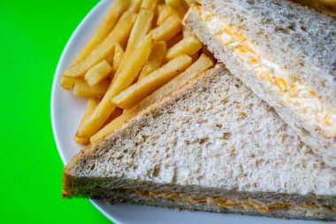 Londra İngiltere, 14 Temmuz 2025, taze yapılmış lezzetli peynirli ve soğanlı sandviç ve patates kızartması.