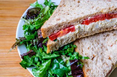 Londra İngiltere, 14 Temmuz 2025, taze yumurta ve salata kremalı domatesli sandviç ve yeşil salata yapraklı.