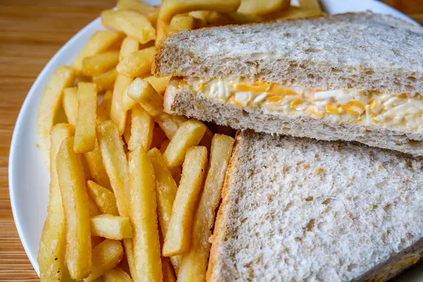 Londra İngiltere, 14 Temmuz 2025, taze yapılmış lezzetli peynirli ve soğanlı sandviç ve patates kızartması.