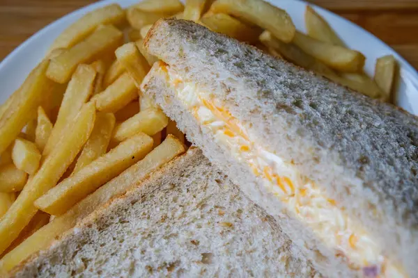 Londra İngiltere, 14 Temmuz 2025, taze yapılmış lezzetli peynirli ve soğanlı sandviç ve patates kızartması.