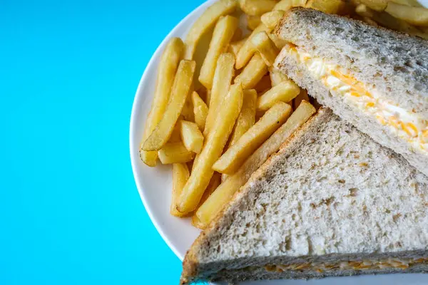 Londra İngiltere, 14 Temmuz 2025, taze yapılmış lezzetli peynirli ve soğanlı sandviç ve patates kızartması.