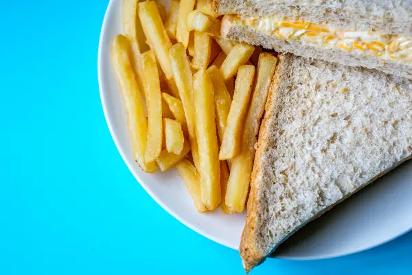 Londra İngiltere, 14 Temmuz 2025, taze yapılmış lezzetli peynirli ve soğanlı sandviç ve patates kızartması.