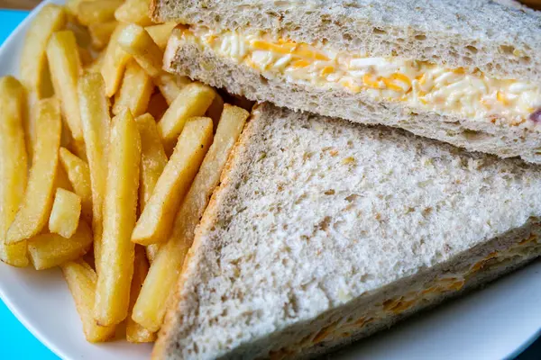 Londra İngiltere, 14 Temmuz 2025, taze yapılmış lezzetli peynirli ve soğanlı sandviç ve patates kızartması.