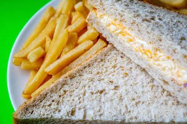 Londra İngiltere, 14 Temmuz 2025, taze yapılmış lezzetli peynirli ve soğanlı sandviç ve patates kızartması.