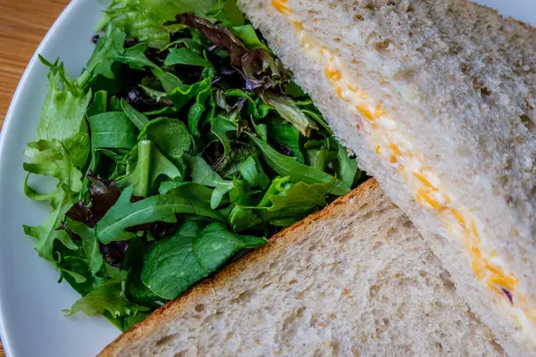 Londra İngiltere, 14 Temmuz 2025, Taze yapılmış Lezzetli Peynir ve Yeşil Salata Yapraklı Soğanlı Sandviç