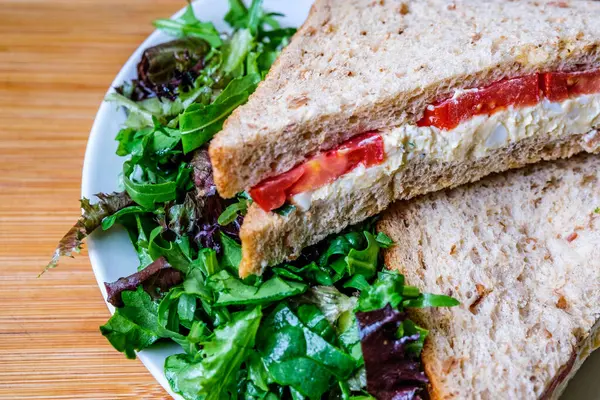 Londra İngiltere, 14 Temmuz 2025, taze yumurta ve salata kremalı domatesli sandviç ve yeşil salata yapraklı.