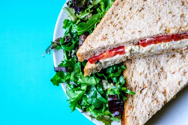 Londra İngiltere, 14 Temmuz 2025, taze yumurta ve salata kremalı domatesli sandviç ve yeşil salata yapraklı.