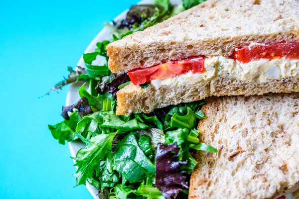 Londra İngiltere, 14 Temmuz 2025, taze yumurta ve salata kremalı domatesli sandviç ve yeşil salata yapraklı.