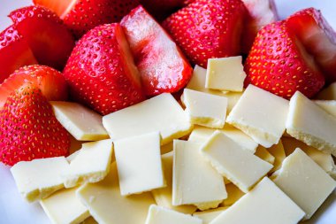 Londra İngiltere, 15 Temmuz 2025, Taze Organik Dilimlenmiş Çilekler Kırık Beyaz Çikolata Kareleri