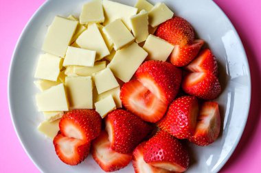 Londra İngiltere, 15 Temmuz 2025, Taze Organik Dilimlenmiş Çilekler Kırık Beyaz Çikolata Kareleri