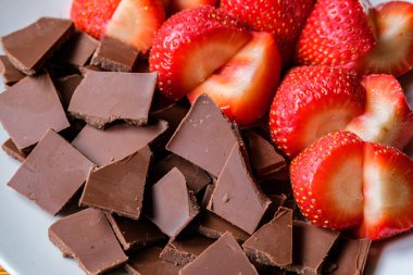 Londra İngiltere, 15 Temmuz 2025, Dilimlenmiş taze organik çilekler Kırık Süt Çikolatası ile