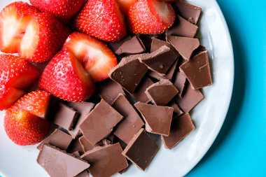 Londra İngiltere, 15 Temmuz 2025, Dilimlenmiş taze organik çilekler Kırık Süt Çikolatası ile