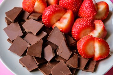 Londra İngiltere, 15 Temmuz 2025, Dilimlenmiş taze organik çilekler Kırık Süt Çikolatası ile