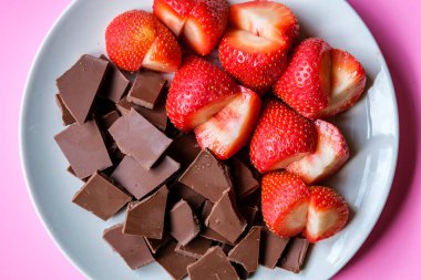 Londra İngiltere, 15 Temmuz 2025, Dilimlenmiş taze organik çilekler Kırık Süt Çikolatası ile