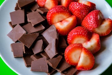 Londra İngiltere, 15 Temmuz 2025, Dilimlenmiş taze organik çilekler Kırık Süt Çikolatası ile