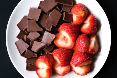 Londra İngiltere, 15 Temmuz 2025, Dilimlenmiş taze organik çilekler Kırık Süt Çikolatası ile