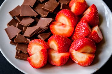 Londra İngiltere, 15 Temmuz 2025, Dilimlenmiş taze organik çilekler Kırık Süt Çikolatası ile