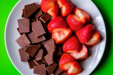 Londra İngiltere, 15 Temmuz 2025, Dilimlenmiş taze organik çilekler Kırık Süt Çikolatası ile