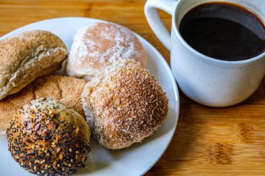 Londra İngiltere, 15 Temmuz 2025, Fırında pişmiş Mini Ekmek Ekmekleri ve bir kupa siyah kahve.