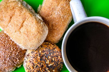 Londra İngiltere, 15 Temmuz 2025, Fırında pişmiş Mini Ekmek Ekmekleri ve bir kupa siyah kahve.