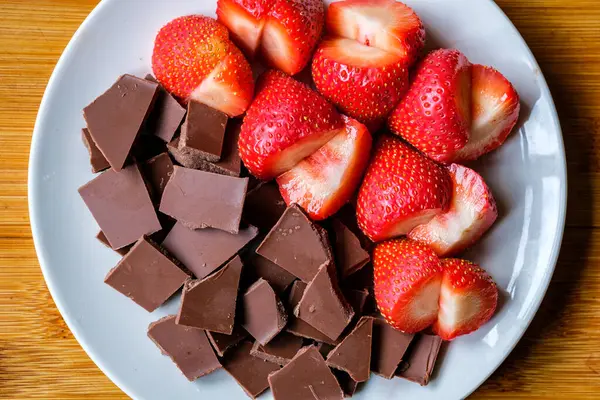 Londra İngiltere, 15 Temmuz 2025, Dilimlenmiş taze organik çilekler Kırık Süt Çikolatası ile