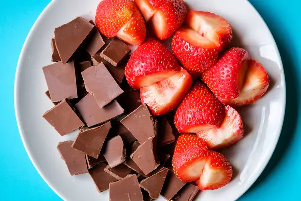 Londra İngiltere, 15 Temmuz 2025, Dilimlenmiş taze organik çilekler Kırık Süt Çikolatası ile