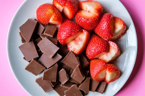 Londra İngiltere, 15 Temmuz 2025, Dilimlenmiş taze organik çilekler Kırık Süt Çikolatası ile